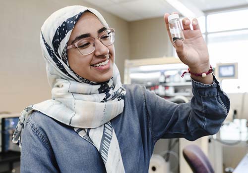 International student in the lab holding a small jar
