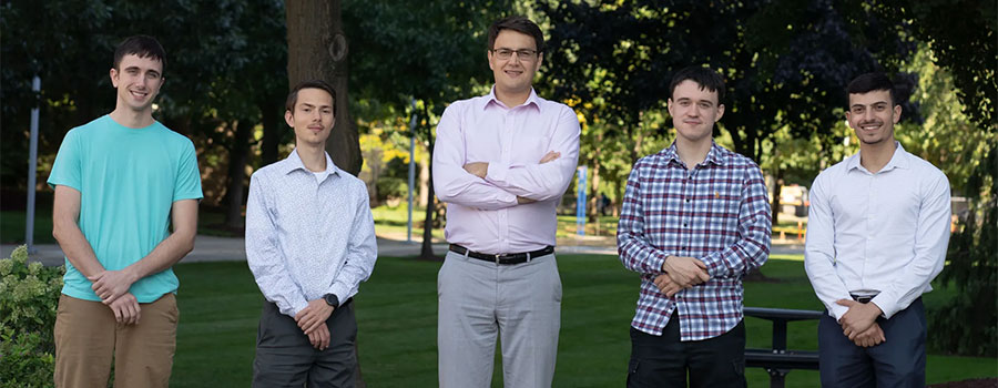 One professor and four graduate students under a tree on campus