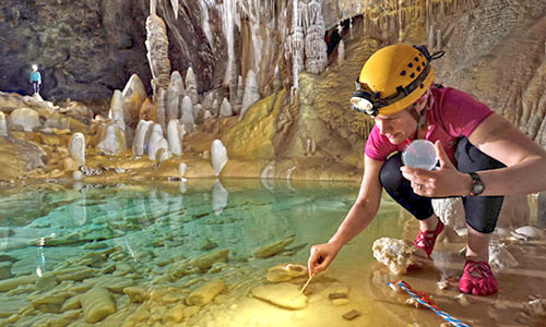 A professor at The University of Akron inside a cave with a pool of water