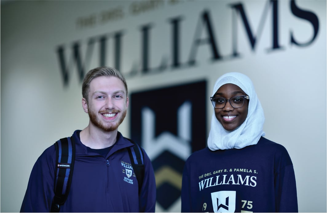 Two students standing inside Williams Honor College Building.