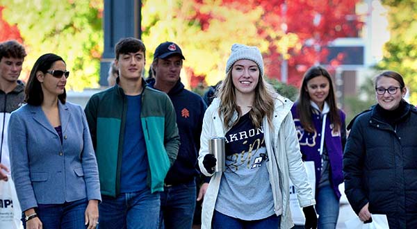A student leads a tour of campus for students and parents